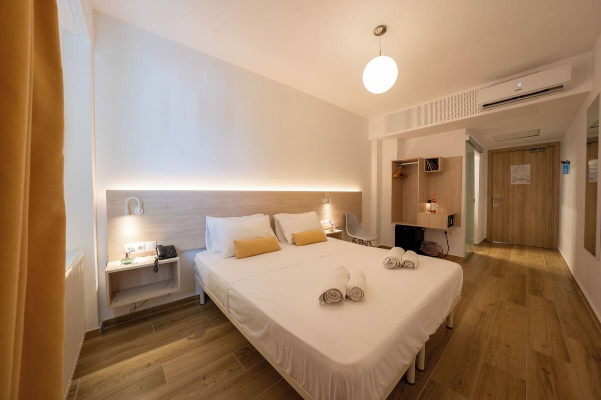 A modern hotel room with a large bed, bedside tables, a desk, and a chair.
