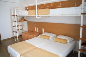 Habitación con literas, cabecero de madera, mesita de noche de madera y armario.