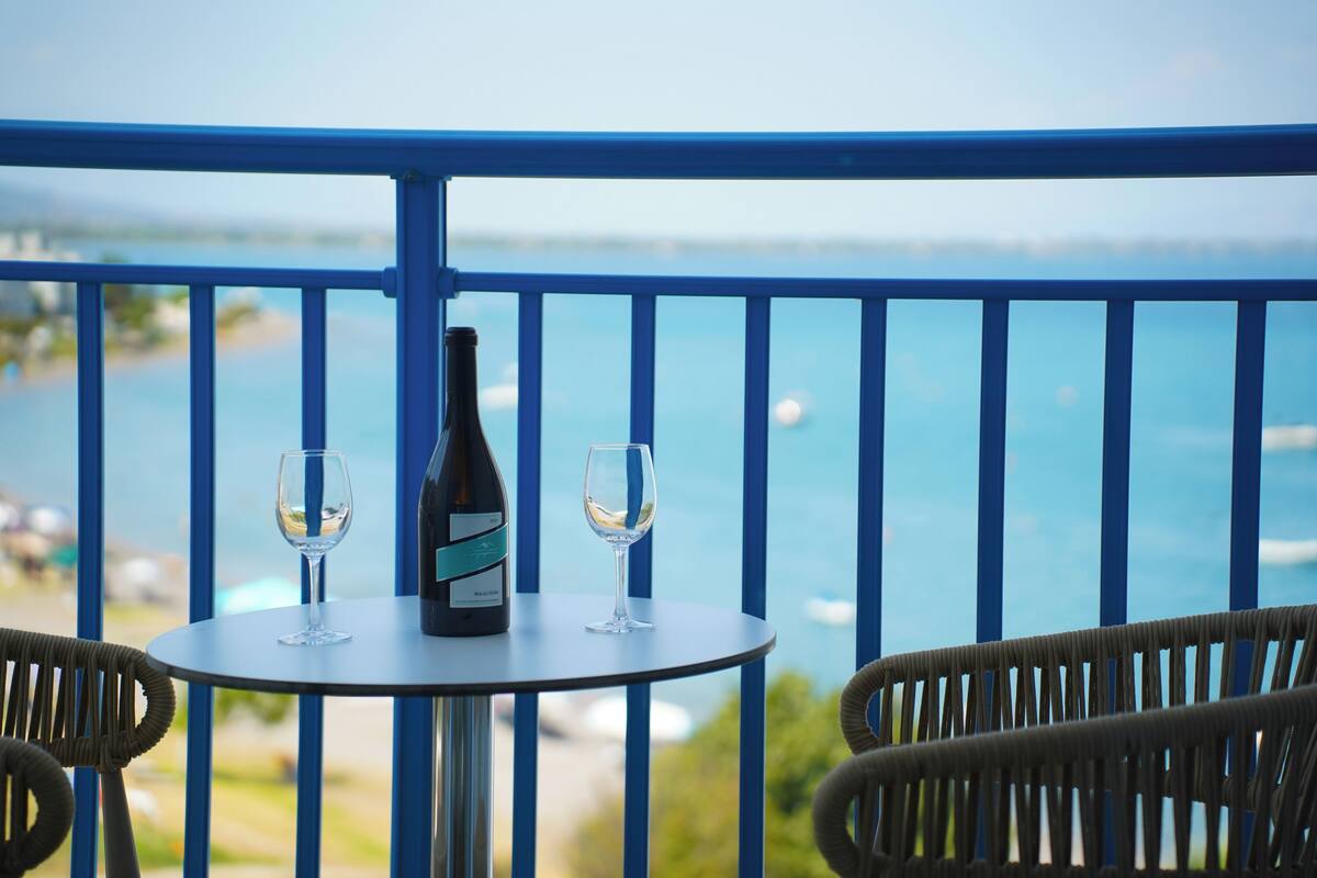 A balcony with a table, two wine glasses, and a bottle of wine.