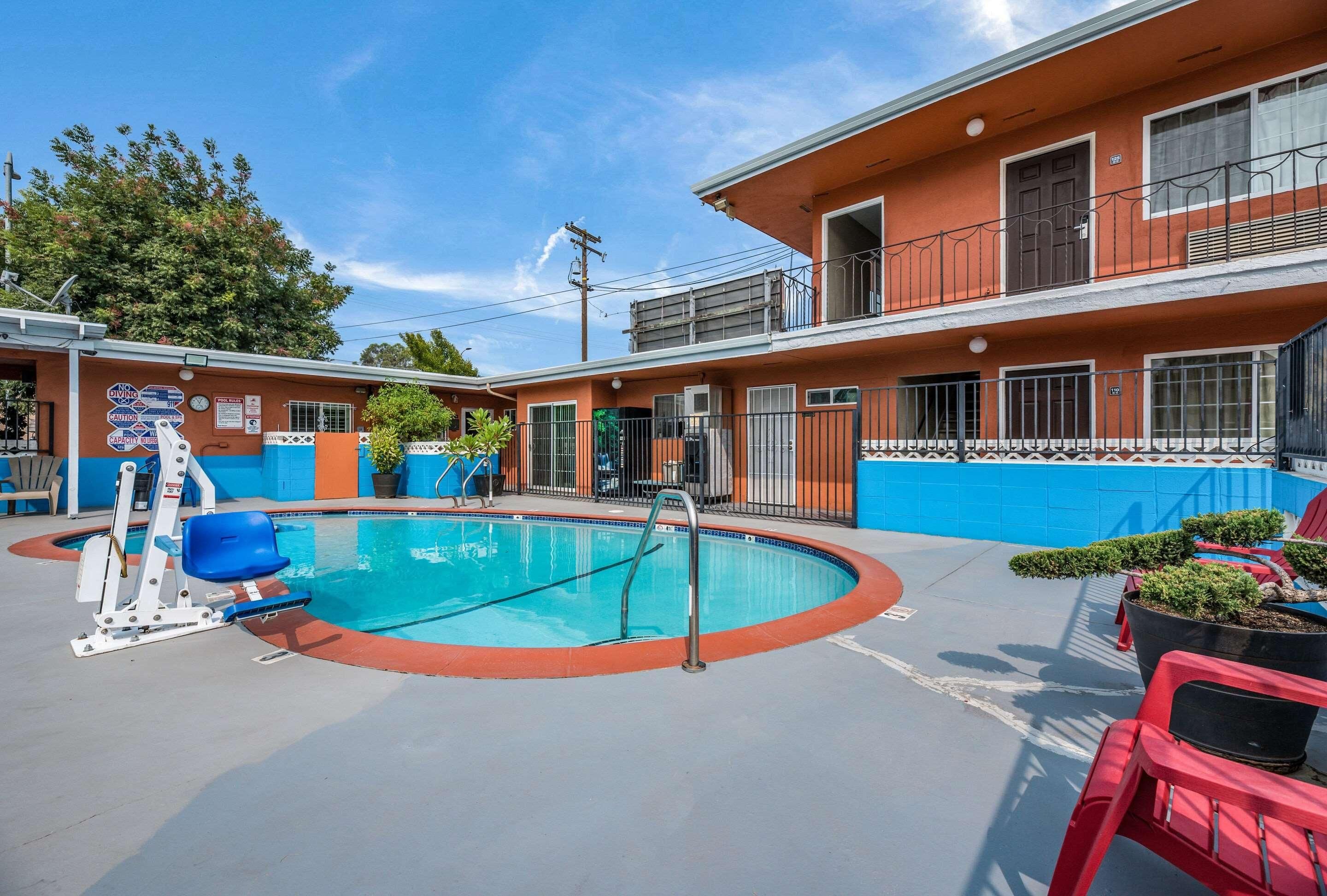 A two-story building with a swimming pool, outdoor seating, and a blue and orange color scheme.