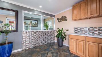 A kitchen with a tiled backsplash, wooden cabinets, and potted plants.