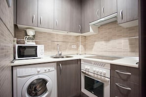 Una cuina compacta amb rentadora, microones, rentatges i forn.