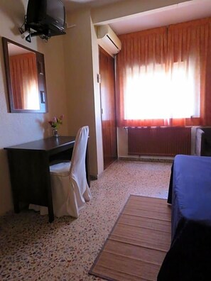 A hotel room with a desk, chair, bed, and a window with curtains. - Hotel Alain (Silla)