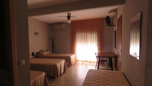 A hotel room with two single beds, a desk, a chair, a ceiling fan, and a window with curtains. - Hotel Alain (Silla)