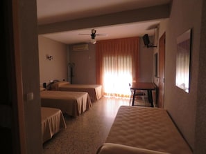 A hotel room with two single beds, a desk, a chair, a ceiling fan, and a window with curtains. - Hotel Alain (Silla)