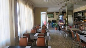 A restaurant with tables and chairs, a ceiling fan, and a television screen.