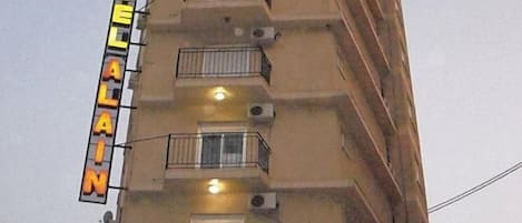 A hotel with a sign indicating 'HOTEL ALAIN' and a 'SALON COLISEO BAR RESTAURANT' below.