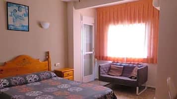 Un dormitorio con cama, ventilador de techo, ventana con cortinas, sofá y lámpara fijada a la pared.