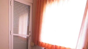 A room with a sofa, a door with a window, and a patterned floor.