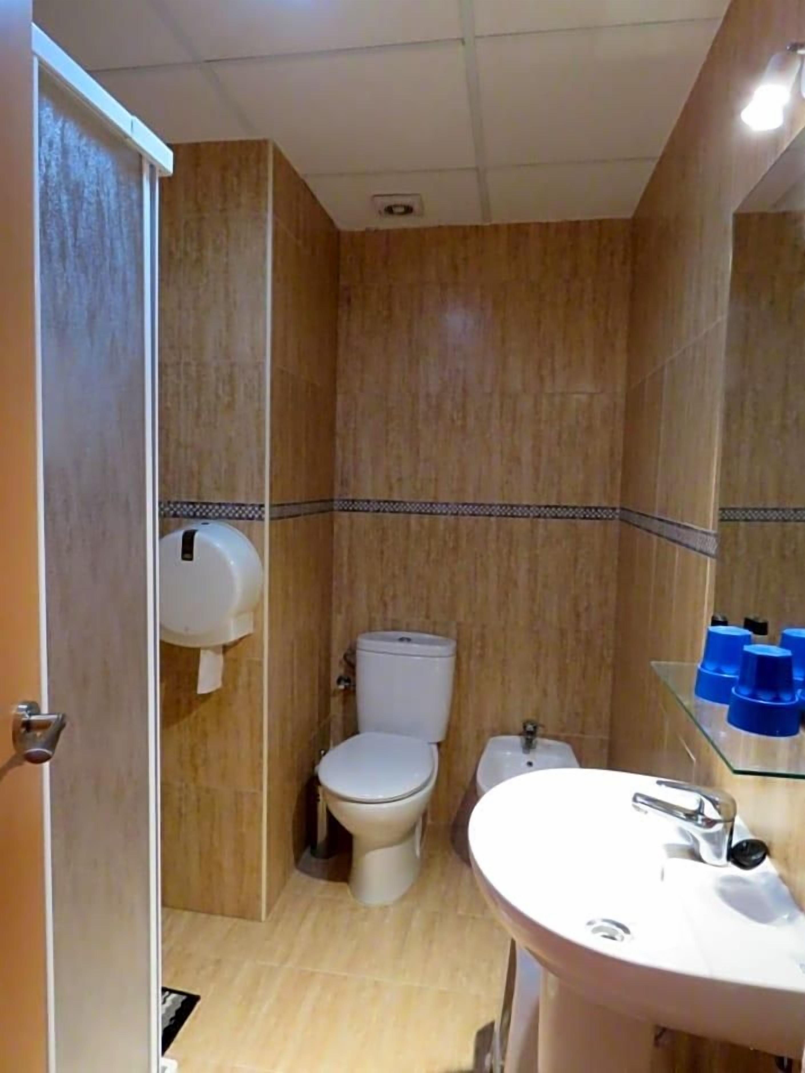 A bathroom with a toilet, sink, and paper towel dispenser.