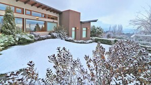 A modern building with large windows and a snow-covered landscape. - Monasterio Hotel Boutique (San Carlos de Bariloche)