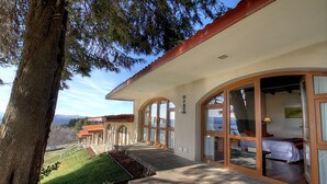 A modern hotel with large glass windows, a covered outdoor area, and a view of the surrounding landscape. - Monasterio Hotel Boutique (San Carlos de Bariloche)