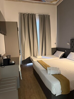 A hotel room with two beds, a desk with a coffee maker, and a window with curtains. - Conte House (Rome)