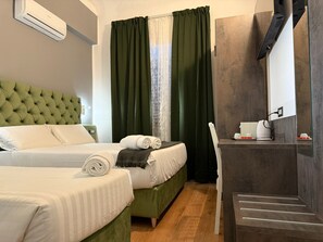 A hotel room with two beds, a green headboard, a coffee maker, and a mirror. - Conte House (Rome)