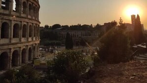 Un bâtiment historique doté de nombreuses arcades, avec un soleil couchant en arrière-plan.