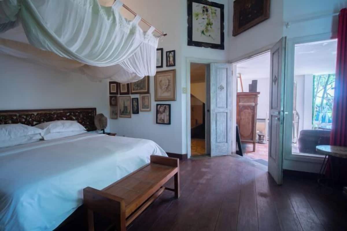 A bedroom with a bed, wooden bench, and a door leading to a balcony.