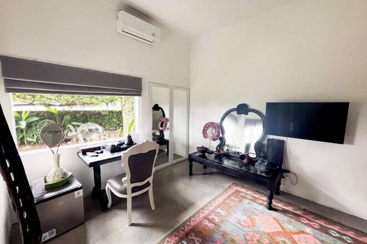 A room with a desk, chair, air conditioning unit, and a large mirror.
