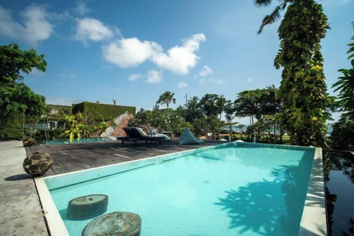 A swimming pool with lounge chairs and tropical vegetation.
