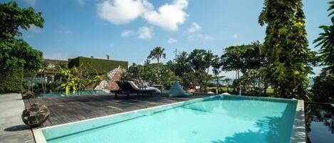 A swimming pool with lounge chairs and tropical vegetation.