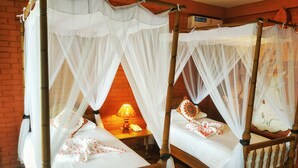 Two four-poster beds with white canopies, wooden headboards, and a brick wall background. - Bagan Village Resort Hotel (Nyaung-U)