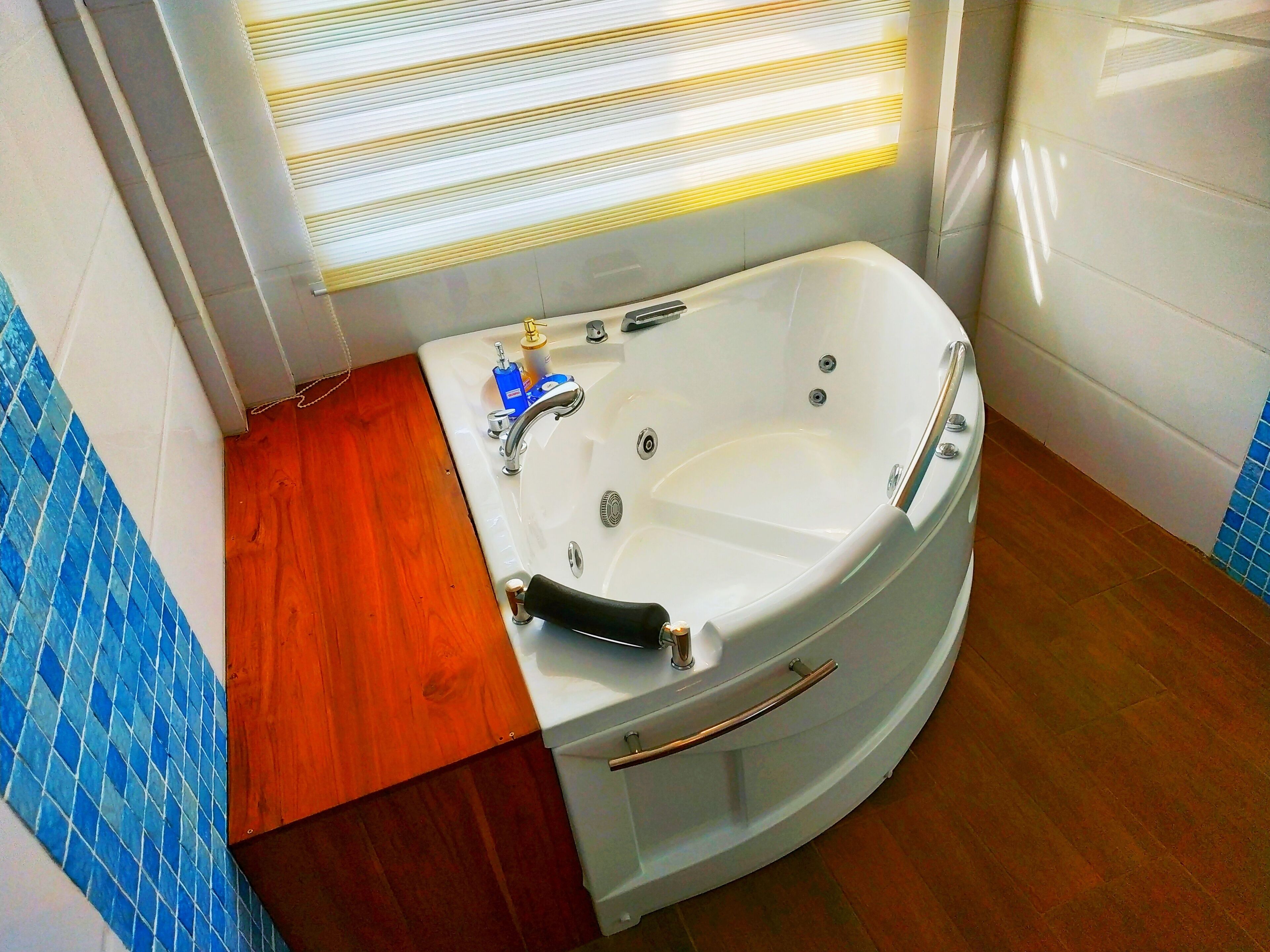 Un baño con una bañera blanca, tocador de madera y paredes con azulejos azules.