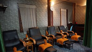 A room with brick walls, leather chairs, wooden side tables, and a clock on the wall. - Bagan Village Resort Hotel (Nyaung-U)