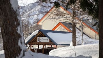 A snow-covered outdoor area with a canopy labeled "Canopy Costa Rica" and a building with a red roof in the background.