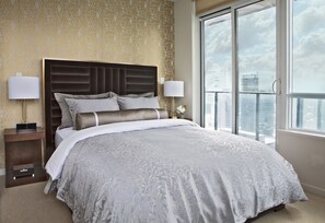 Relax in a spacious room with a large bed, two bedside tables, and a window offering a city view.