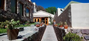 Un estrecho sendero de piedra que lleva a un edificio con fachada blanca y puerta de madera.