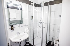 Une salle de bain moderne avec une douche à parois de verre, un lavabo blanc et un miroir au-dessus du lavabo.