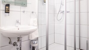 Une salle de bain moderne avec une douche à parois de verre, un lavabo blanc et un miroir au-dessus du lavabo.