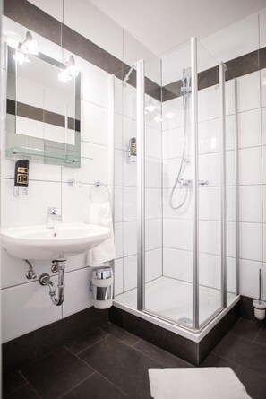 Une salle de bain moderne avec une douche à parois de verre, un lavabo blanc et un miroir au-dessus du lavabo.