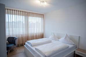 Une chambre d’hôtel moderne avec un grand lit, une chaise et une table de chevet.
