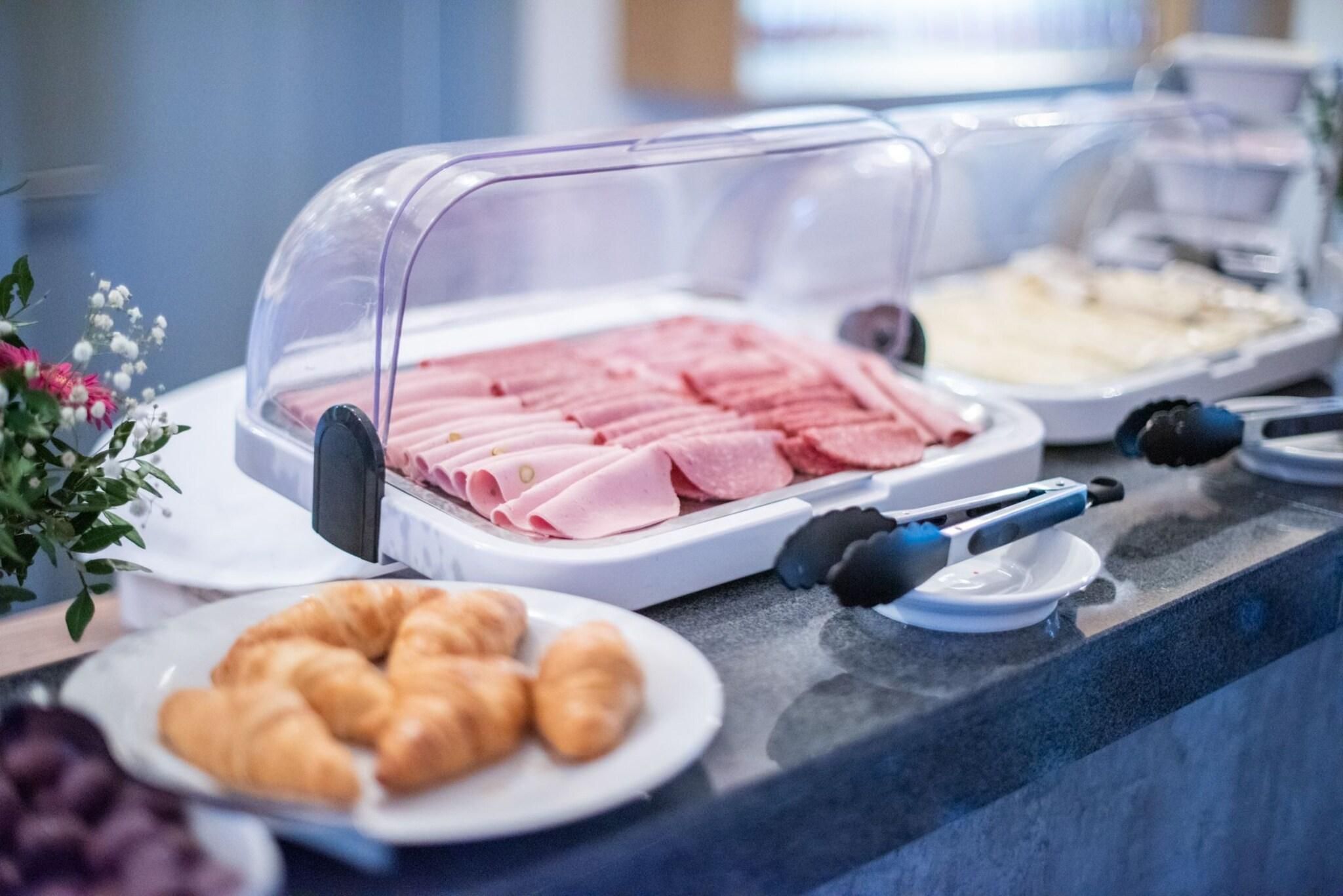 En buffetvogn med forskellige spiser, herunder pålæg og kager, samt en kaffemaskine.