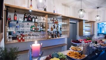 Eine Bar mit Regalen voller Spirituosenflaschen und Gläsern, einer Kerze und einer Obstplatte.