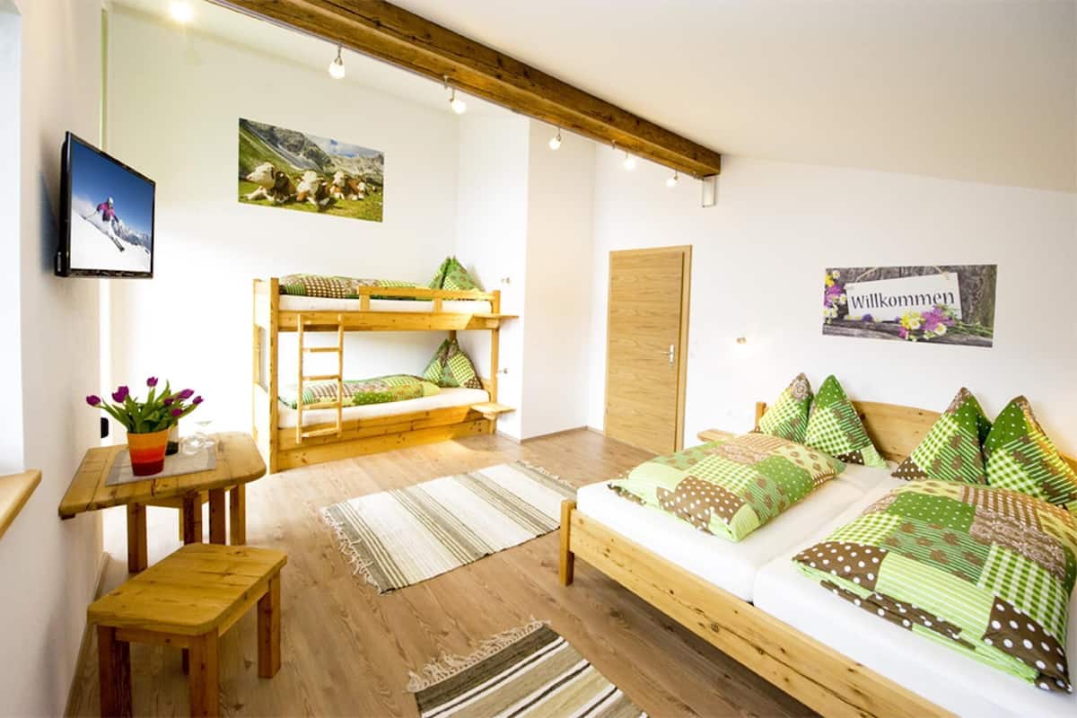 Ein Zimmer mit Etagenbett, einem Einzelbett, Holzmöbeln, einem Fernseher und einem Willkommensschild.