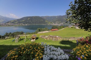 A lakeside view with a playground, wooden structures, and a red-roofed building. - Alpenhof Grafleiten (Zell am See)