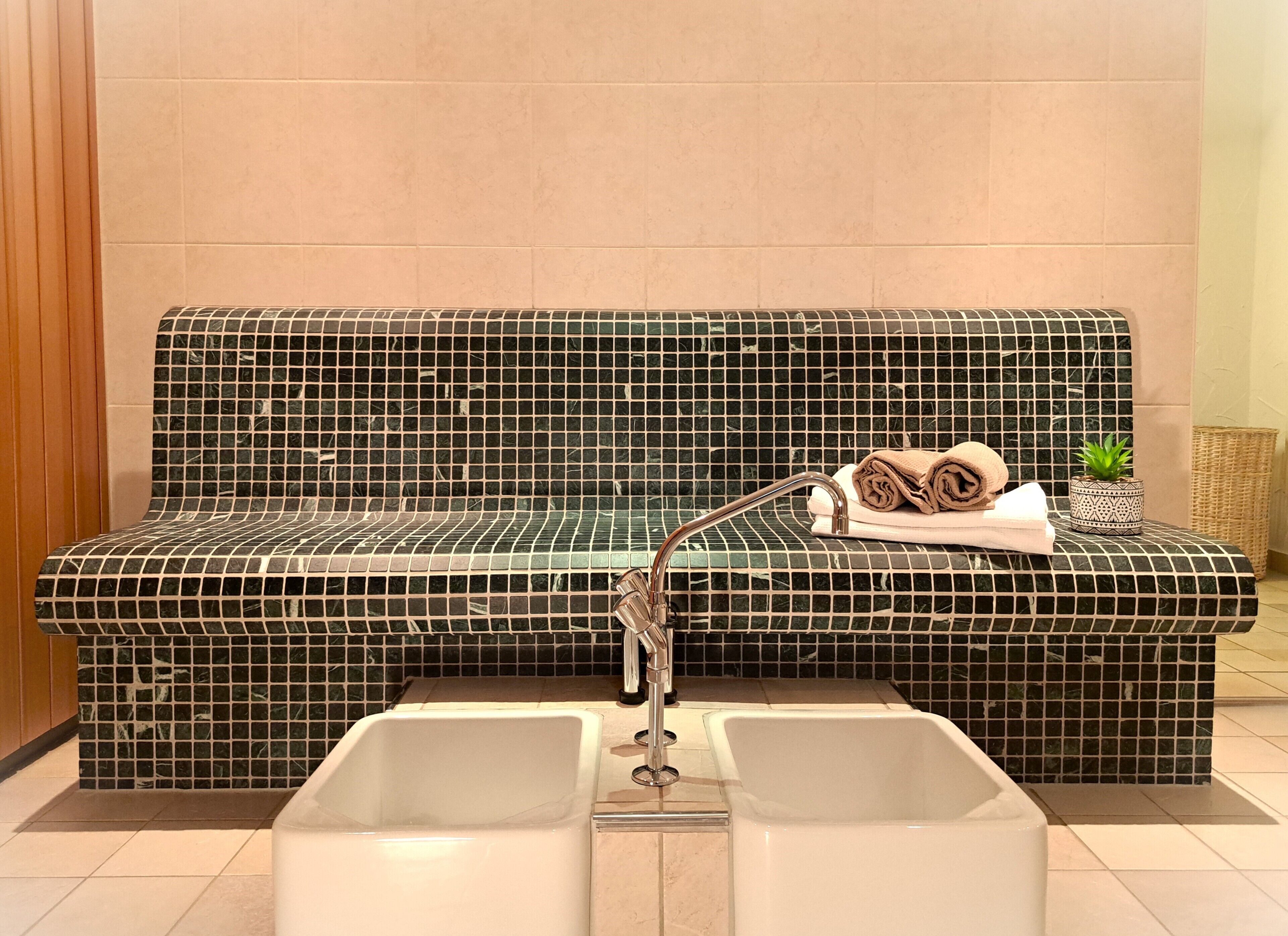 Un baño con un banco de azulejos, un lavabo y una pequeña planta en maceta.