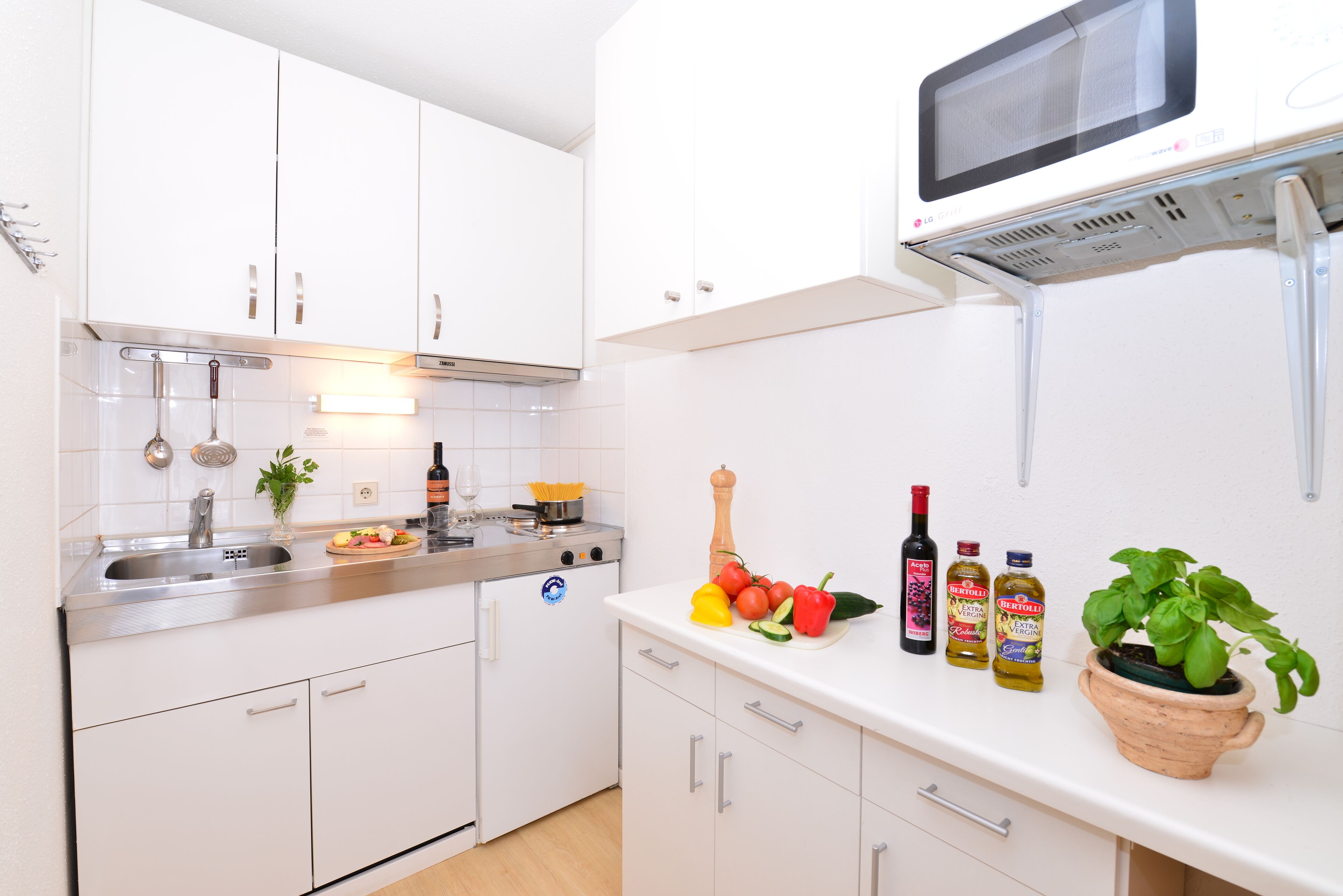 A modern kitchen with white cabinets, stainless steel appliances, and a microwave above the counter.