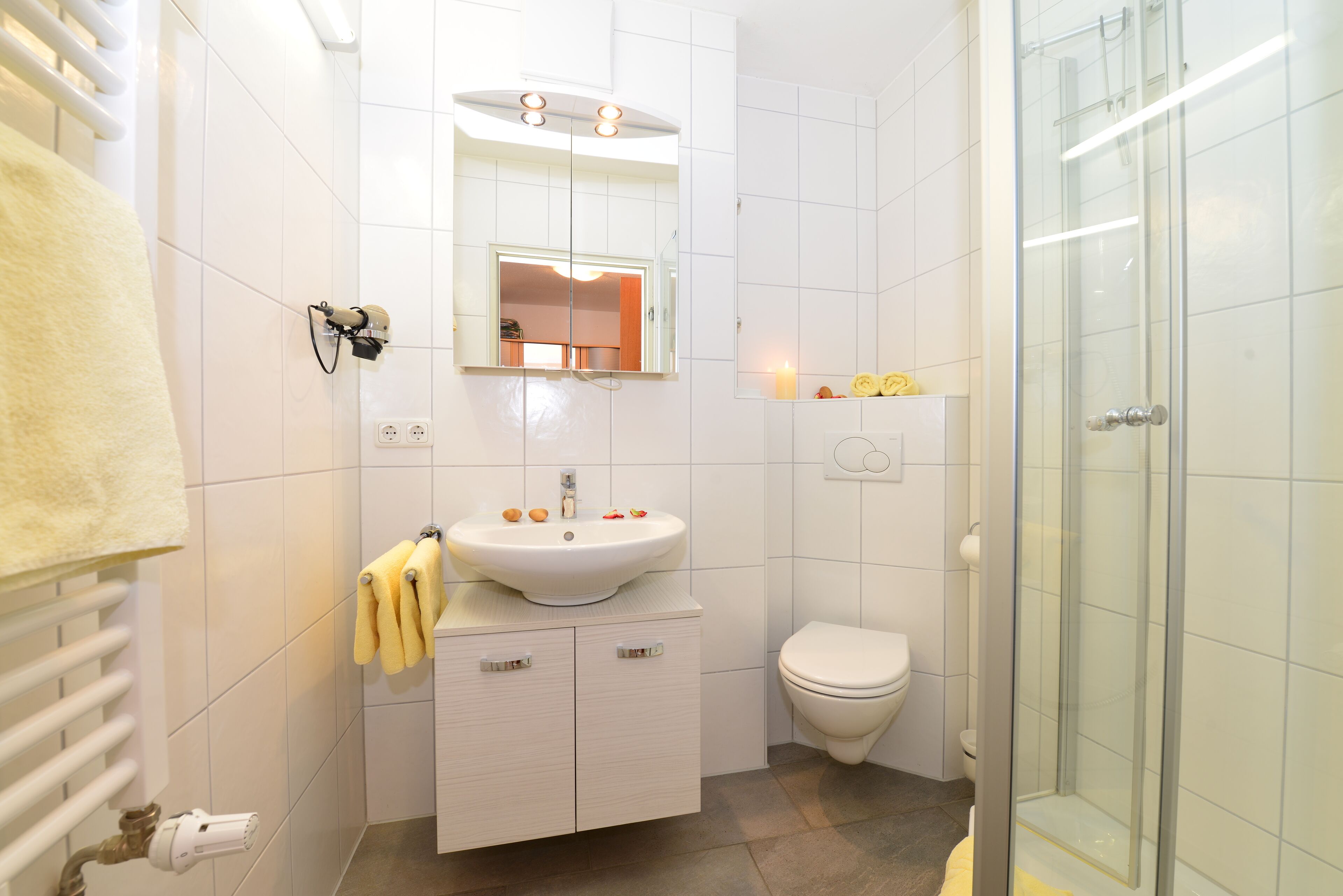 A modern bathroom with a white sink, mirror, and toilet.