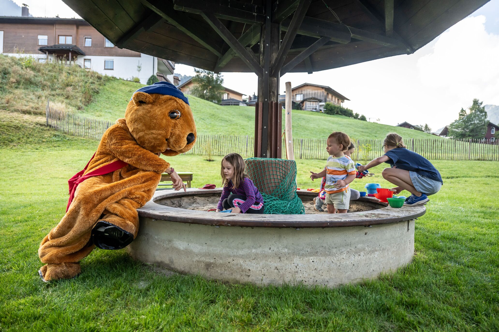 A concrete play area with a bear mascot and children playing.