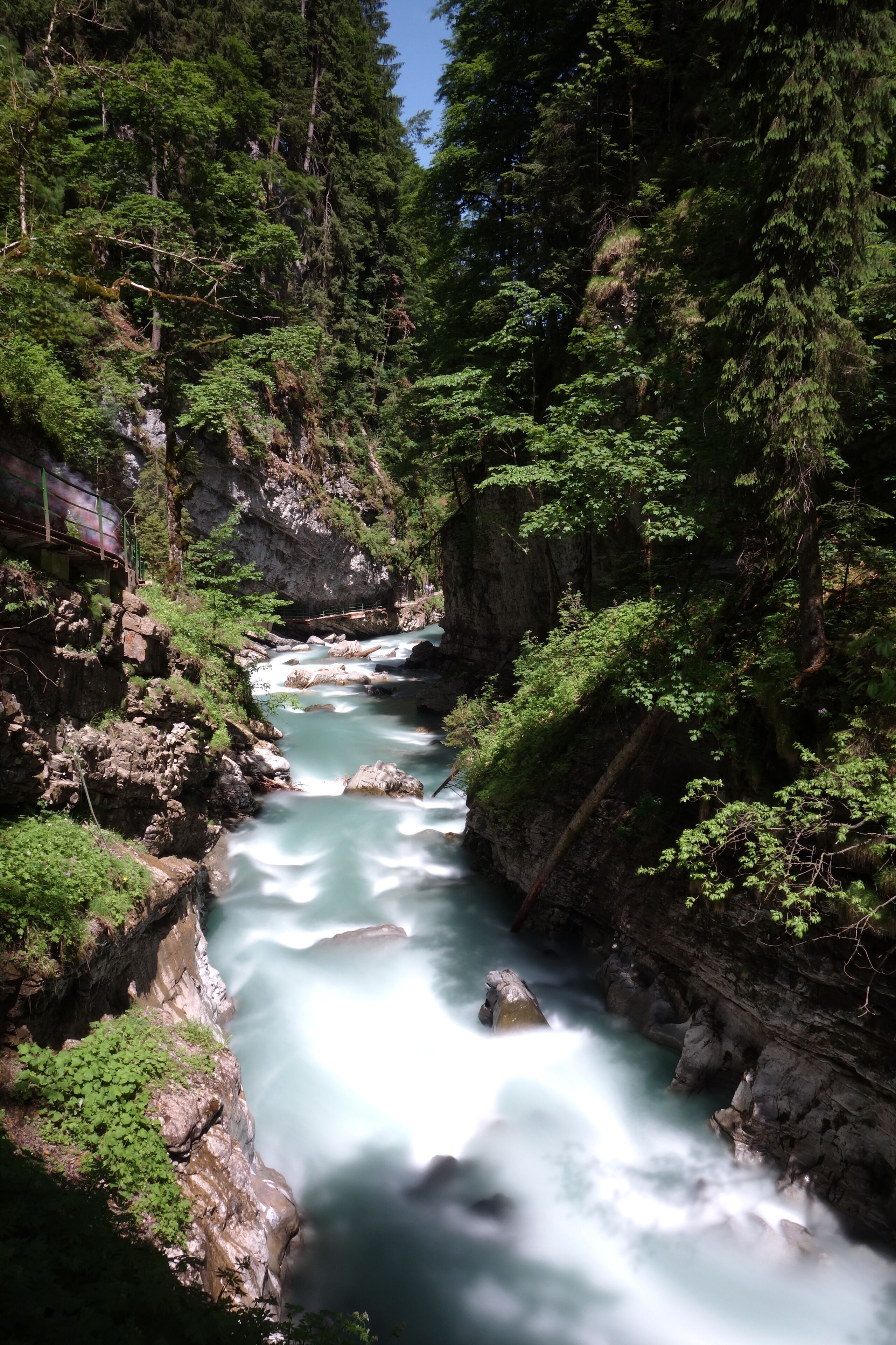 A river flowing through a forested gorge with rocky cliffs and dense greenery.