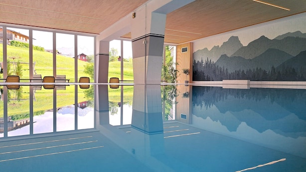 A large indoor swimming pool with clear glass walls, a mountain mural, and a seating area with chairs. - Familienhotel Kleinwalsertal (Mittelberg)