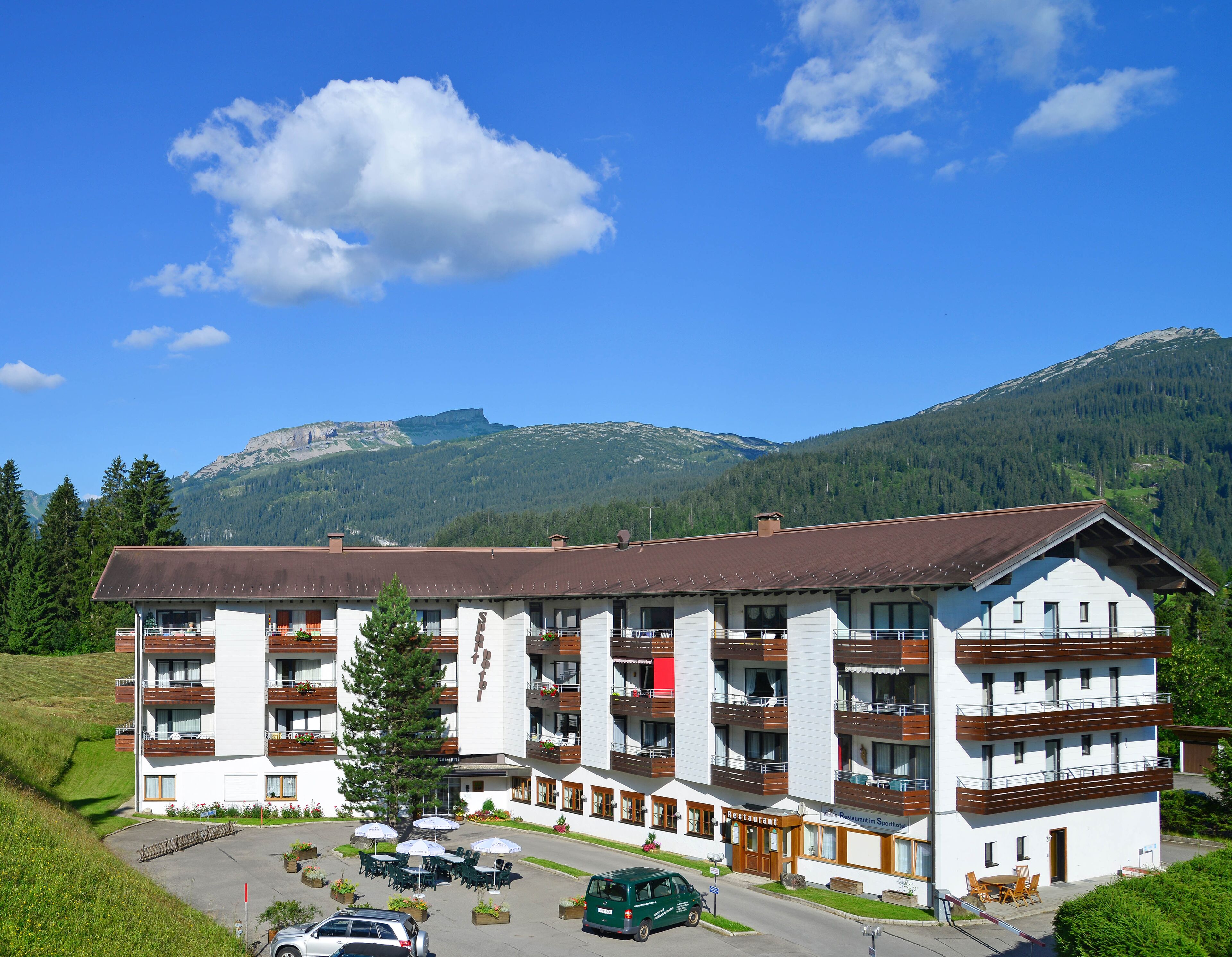 A multi-story hotel with balconies, a restaurant, and a parking area.
