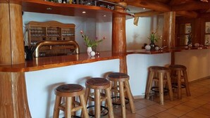 A wooden bar area with stools, shelves with bottles, and a decorative vase with flowers. - Am Edersee (Edertal)