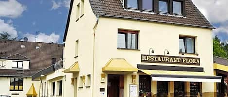 A two-story building with a sign reading "RESTAURANT FLORA".