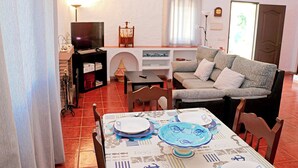 A living room with a sofa, a dining table set with plates, a TV, and a bookshelf.