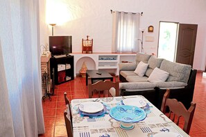 A living room with a sofa, a dining table set with plates, a TV, and a bookshelf.