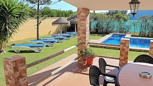 A poolside area with lounge chairs, a table, and a small garden.