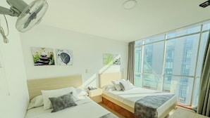 A modern hotel room with two beds, a large window with a city view, and artwork on the walls. - Hotel Alcaravan (Medellin)